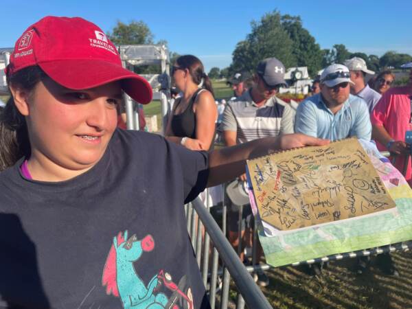 Isabella Lamos shows off autographs she received at the PGA tour in Wilmington