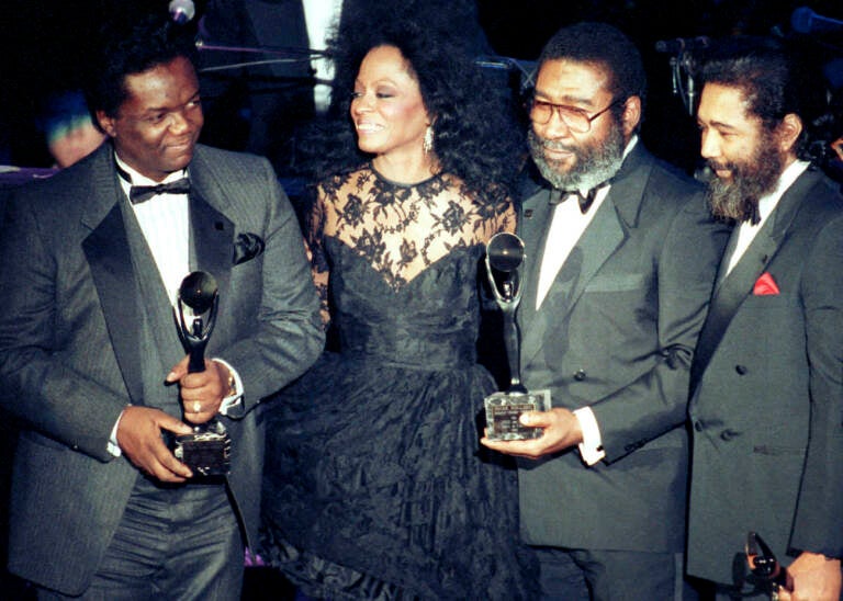 FILE - Singer Diana Ross, second from left, joins songwriters, from left, Lamont Dozier, Brian Holland and Eddie Holland after the writing team was inducted into the Rock and Roll Hall of Fame in New York on Jan. 17, 1990. Dozier, of the celebrated Holland-Dozier-Holland team that wrote and produced “You Can’t Hurry Love,” “Heat Wave” and dozens of other hits and helped make Motown an essential record company of the 1960s and beyond, has died at age 81.  (AP Photo/Ron Frehm, File)