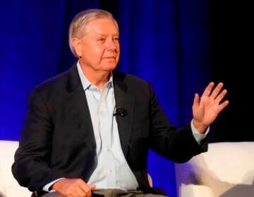 Sen. Lindsey Graham sits in a chair and appears to wave to an audience.