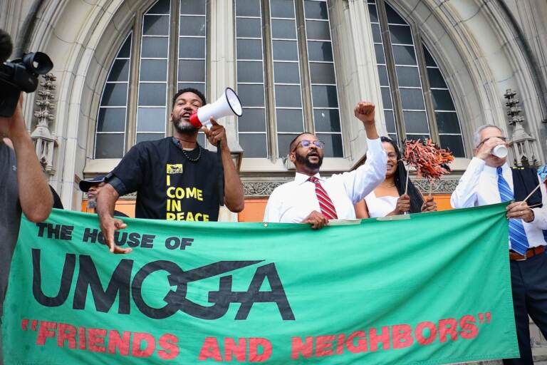 A group of people seem to celebrate as they hold up a green sign that reads, 