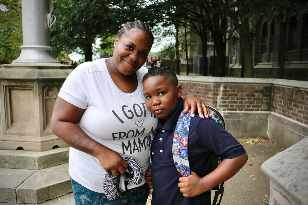 A woman stands with her arm around her son, who is about to go to his first day of school at Overbrook High School.