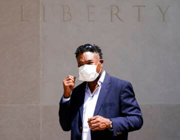 Ken Jenkins begins to take off his face mask as he exits a building.