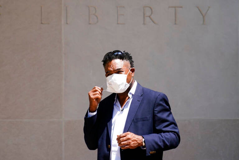 Ken Jenkins begins to take off his face mask as he exits a building.