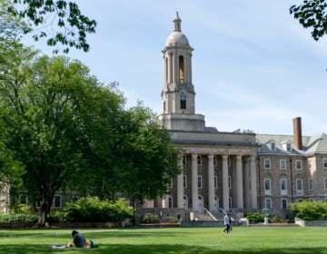 People walk across Old Main lawn on the Penn State campus