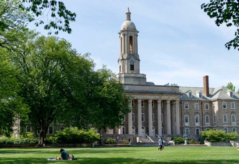 People walk across Old Main lawn on the Penn State campus