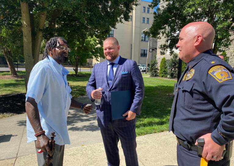 Rodney Dean (left) speaks with Woodbury Junior-Senior High School resource officer Ryan Alcott (middle) and Woodbury Police Chief Thomas Ryan (right) at a press conference announcing a new law requiring New Jersey schools to implement school threat assessment teams. (Tennyson Donyéa / WHYY)