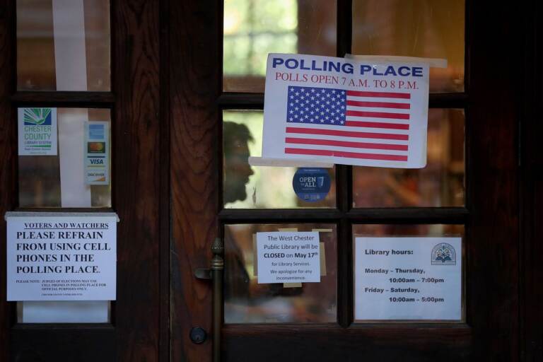 A sign for a polling place is seen on the exterior of a door
