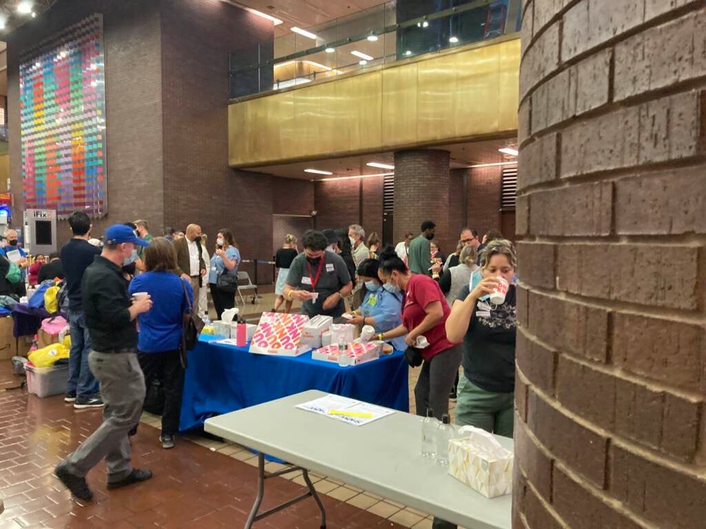 A group of people are gathered around a table in a large lobby.