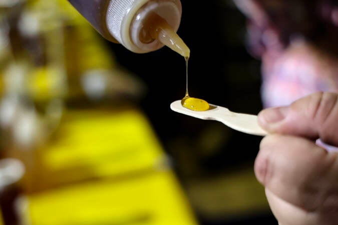 A member of the Philadelphia Beekeepers Guild pours a sample of honey at the Philadelphia Honey Festival. (Kimberly Paynter/WHYY)