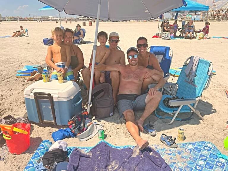 Luc Belanjer (seated) with his family and friends on the beach in Wildwood, N.J. They are among the thousands from the Canadian province of Quebec who decided to spend summer vacation in Cape May County. (P. Kenneth Burns/WHYY)