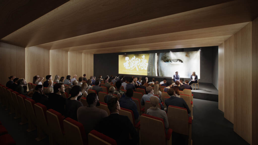 An audience looks on at a performance in a small theater.