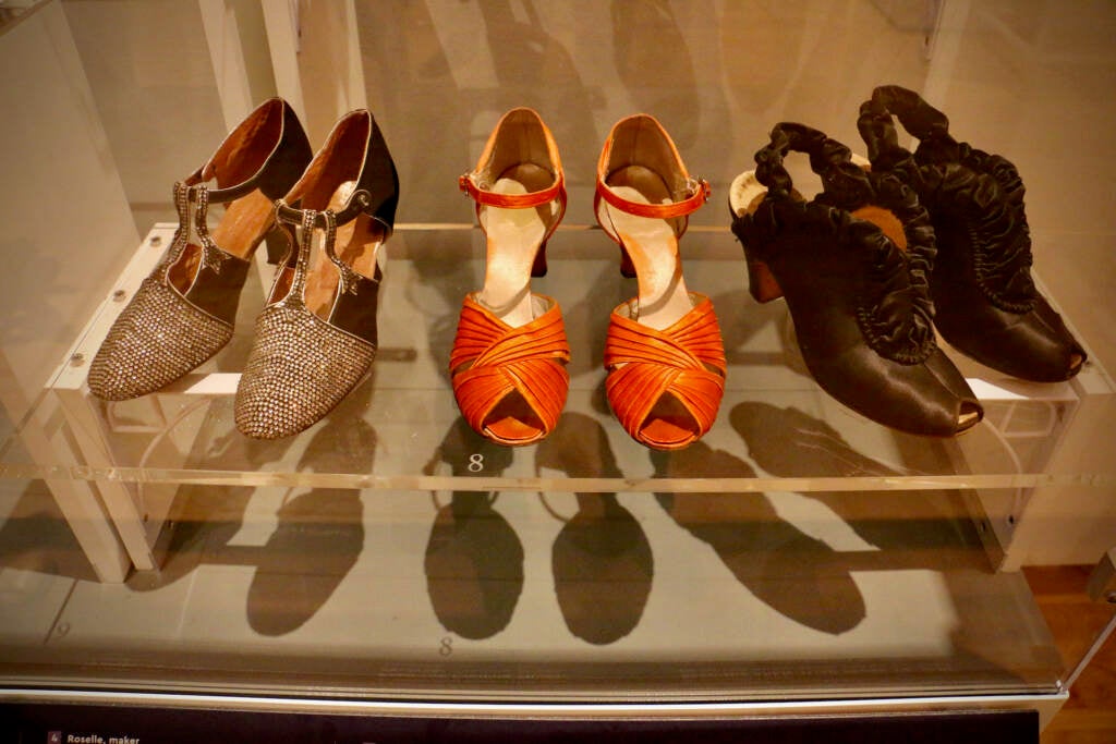 Three pairs of shoes are displayed in a glass case.