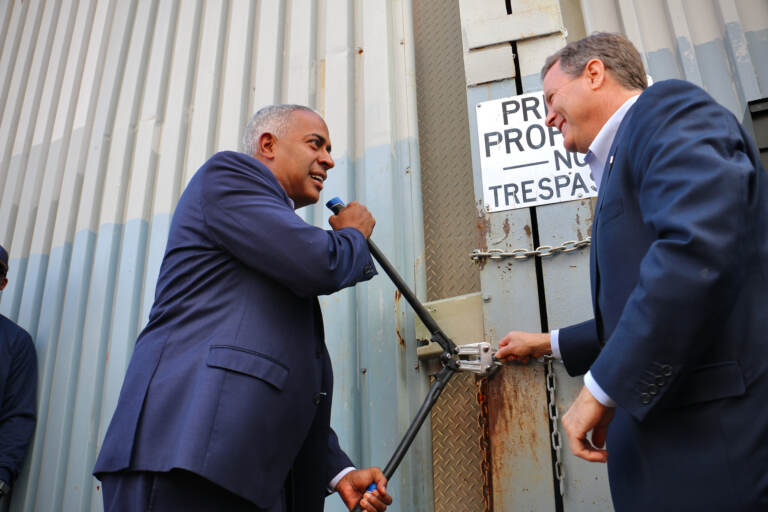 Camden Mayor Vic Carstarphen and Congressman Donald Norcross cut the chain on an illegal dumping site at 7th and Chestnut streets to begin the process of cleaning up a 40-foot-tall mound of debris that has been troubling residents for years. (Emma Lee/WHYY)