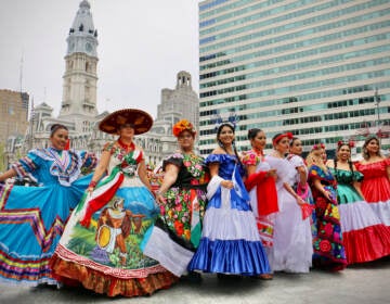 Women in dresses representing Latin American countries pose for photos at the Latin America Thrives in Philadelphia event in Love Park. (Emma Lee/WHYY)