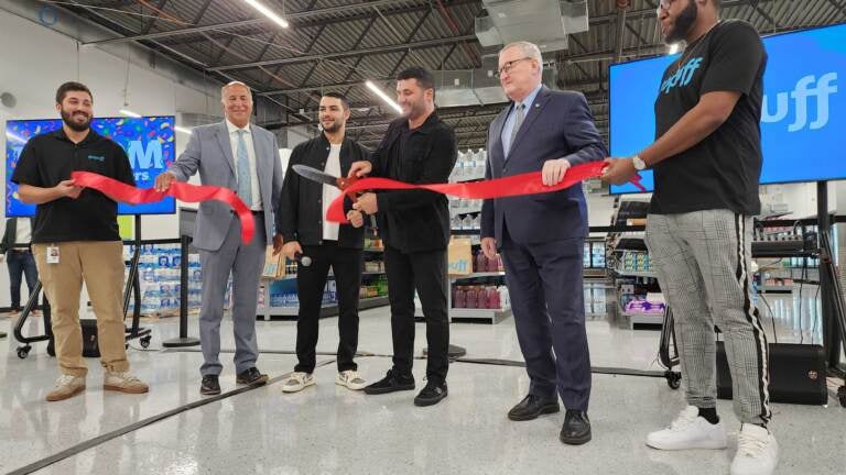 Gopuff co-founder Rafael Ilishayev cuts the ribbon on a new distribution facility in Spring Garden, alongside (starting second from left) Philadelphia City Councilmember Mark Squilla, Gopuff cofounder Yakir Gola and Philadelphia Mayor Jim Kenney. (Tom MacDonald/WHYY)