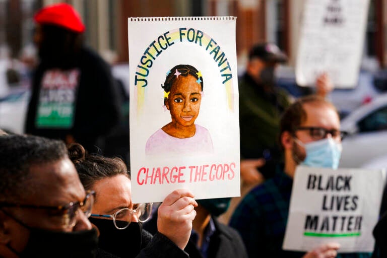 A person holds a sign that reads 