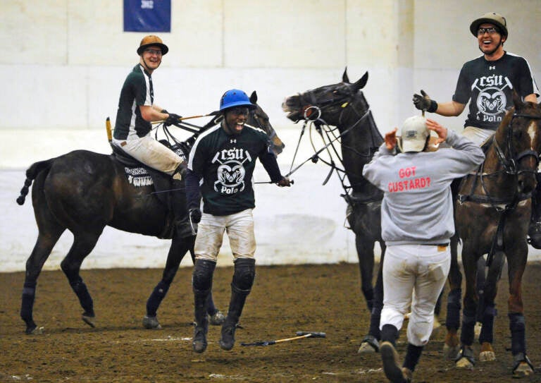 In this Wednesday, April 8, 2015, photo, Colorado State's Kareem Rosser, center, celebrates with his team at the end of a polo match against SMU in the intercollegiate polo championships at the University of Connecticut in Storrs, Conn. Rosser who grew up in poverty in West Philadelphia led Colorado State into the national championship game on Wednesday. About 50 schools field teams in what participants say is no longer just a sport for kings and millionaires. (AP Photo/Jessica Hill)