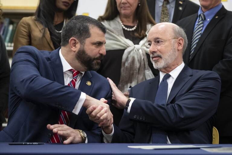 File photo: Pennsylvania Gov. Tom Wolf, right, shakes hands with Rep. Mark Rozzi, D-Berks, after signing legislation into law at Muhlenberg High School in Reading, Pa., Tuesday, Nov. 26, 2019. Wolf approved legislation Tuesday to give future victims of child sexual abuse more time to file lawsuits and to end time limits for police to file criminal charges. (Matt Rourke / AP Photo)