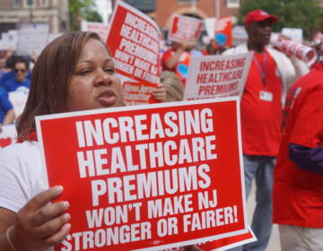 File photo: State workers display their signs during a rally outside New Jersey Statehouse on Sept. 13, 2022. (Tennyson Donyéa/WHYY)