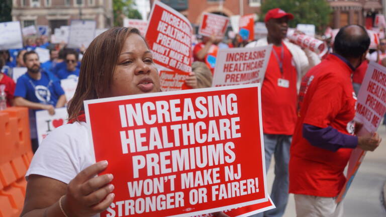 File photo: State workers display their signs during a rally outside New Jersey Statehouse on Sept. 13, 2022. (Tennyson Donyéa/WHYY)