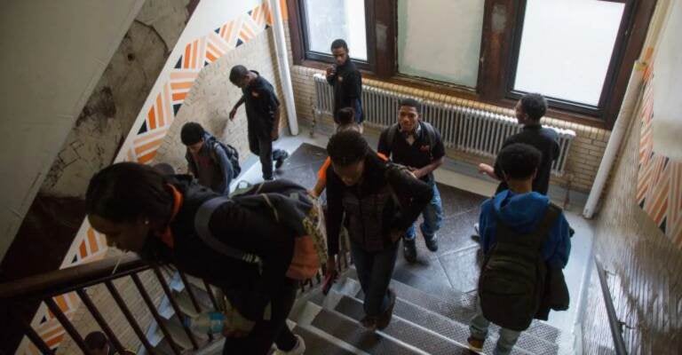 Students pass through a stairwell at Overbrook High School. The school is one of three that will participate in the district’s 21st Century Schools Model initiative where students will pursue workforce training in specific fields related to local needs and interests. (Emily Cohen for WHYY)