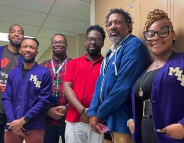 Teachers at Philadelphia’s Martin Luther King High School (from left) Marsalis Chism, Eric Butler, Michael Flemming, Stephen Flemming, and Denzil Flemming stand next to Principal Keisha Wilkins in the school’s hallway. (Johann Calhoun/Chalkbeat)