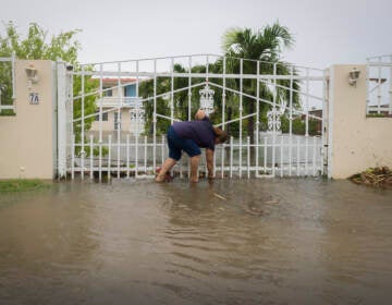 A woman clears debris on her property flooded by Hurricane Fiona in Salinas, Puerto Rico, Monday, Sept. 19, 2022. (Alejandro Granadillo/AP)