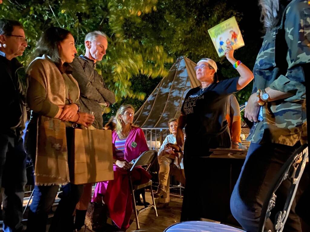 A person holds up a children's book as other people look on.