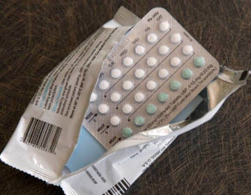 A birth control packet sits unused in open plastic wrapping.