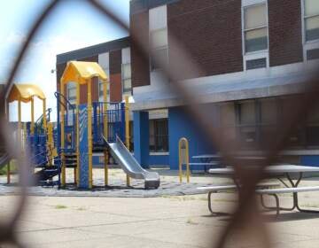 A playground is visible through the links of a fence.