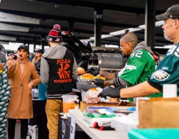 Dave Lee of Pizza Jawn (center right, with serving ladle) brings pizza ovens to his Eagles tailgate, and shares food with dozens of others. (Daviston Jeffers)