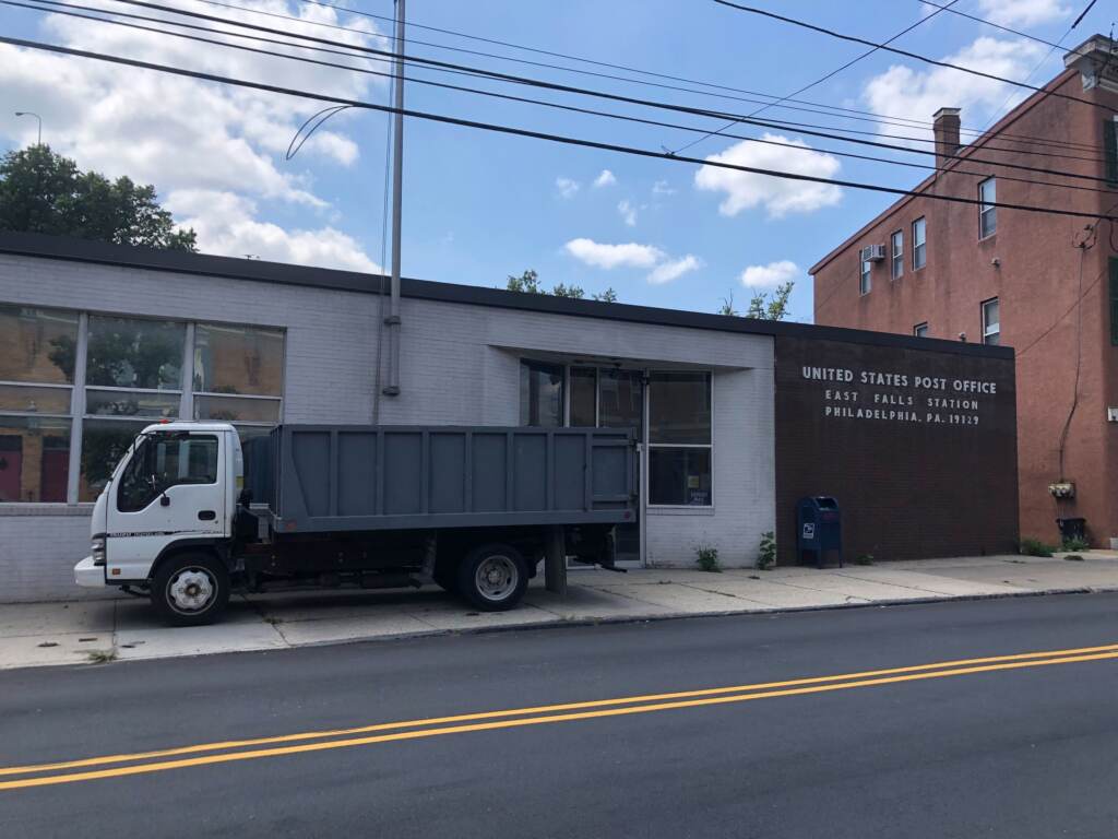 A truck is parked in front of the East Falls Post Office building.