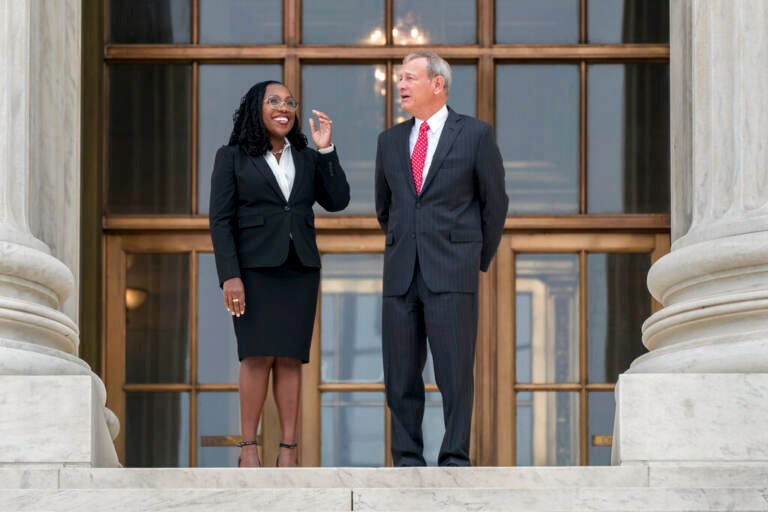 Justice Jackson stands to the left of Justice Roberts outside of a building.