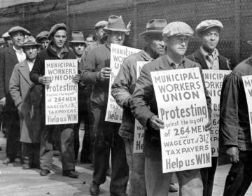 A black-and-white photo shows pictures of men in 1930s attire holding picket signs.