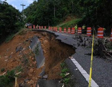 Mud and pieces of a road are falling apart on a highway.