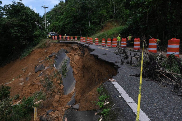 Mud and pieces of a road are falling apart on a highway.