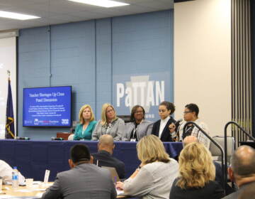 A group of people are seated at a table in front of an audience.