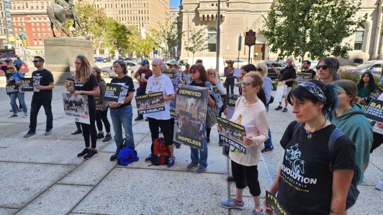 A group of people stand in a semicircle holding signs.