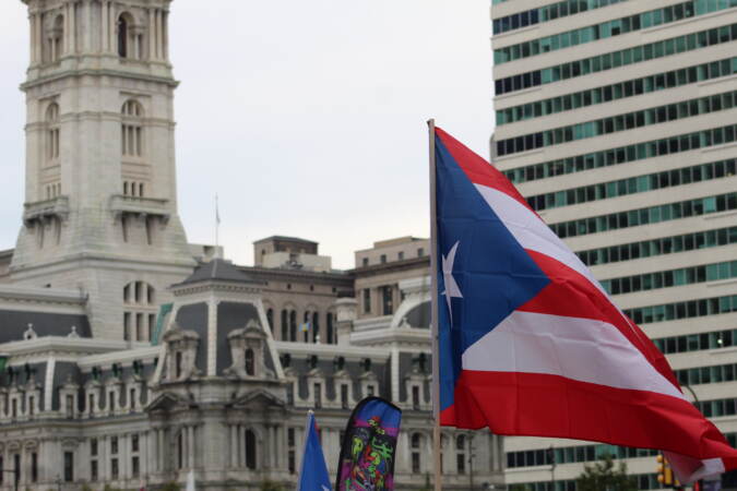 A Puerto Rican flag is visible, with Philadelphia's City Hall in the background.