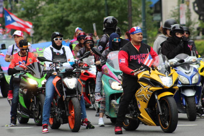 A group of people on motorcylces, some wearing or displaying the Puerto Rican flag.