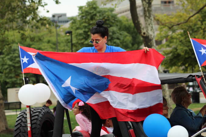 A woman holds up a large Puerto Rican flag.