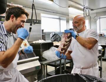 Frank Olivieri (right), owner of Pat’s King of Steaks, holds up a frozen ribeye for punches from Matthew Amira, who will portray Rocky in Walnut Street Theatre’s production of ‘’Rocky, the Musical.’’ (Emma Lee/WHYY)