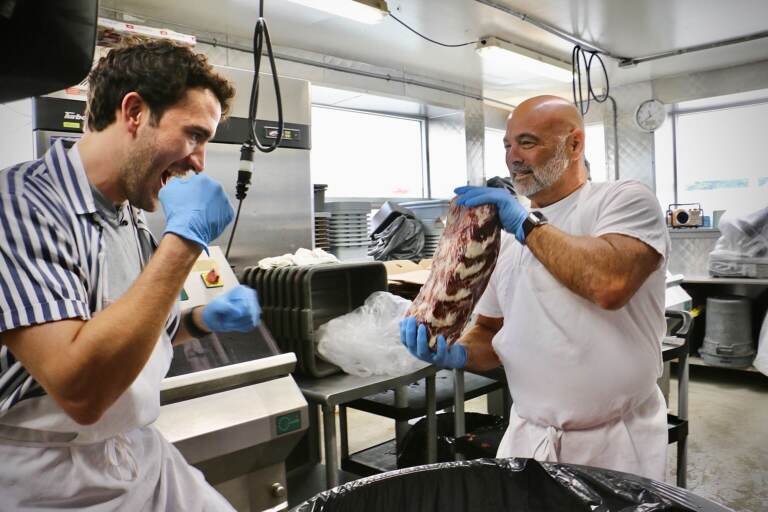 Frank Olivieri (right), owner of Pat’s King of Steaks, holds up a frozen ribeye for punches from Matthew Amira, who will portray Rocky in Walnut Street Theatre’s production of ‘’Rocky, the Musical.’’ (Emma Lee/WHYY)