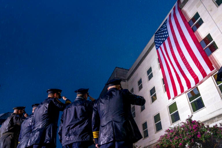 A view of officers from behind saluting the American flag.