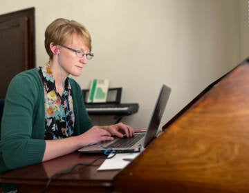 A doctor types on a laptop.