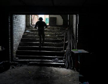 An Ukrainian serviceman walks out of a basement which, according to Ukrainian authorities, was used as a torture cell during the Russian occupation, in the retaken village of Kozacha Lopan, Ukraine, Saturday, Sept. 17, 2022. (AP Photo/Leo Correa)