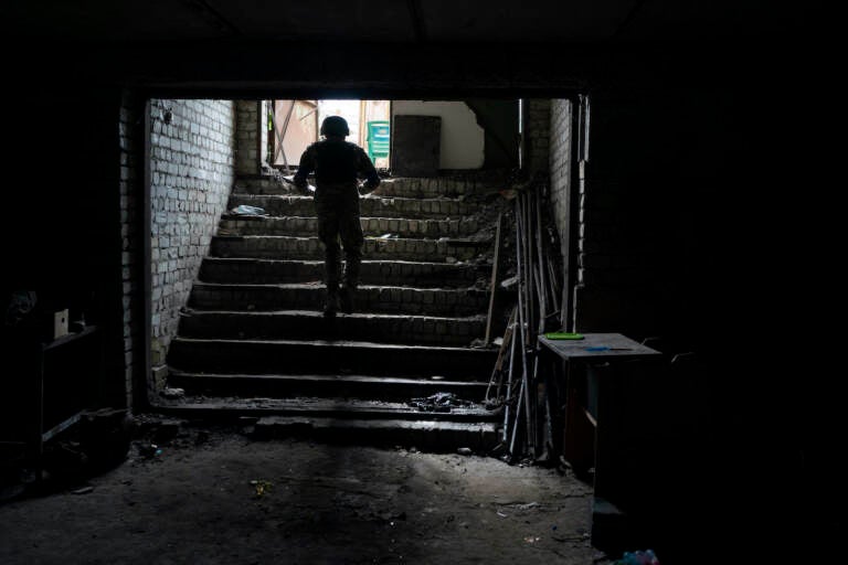 An Ukrainian serviceman walks out of a basement which, according to Ukrainian authorities, was used as a torture cell during the Russian occupation, in the retaken village of Kozacha Lopan, Ukraine, Saturday, Sept. 17, 2022. (AP Photo/Leo Correa)