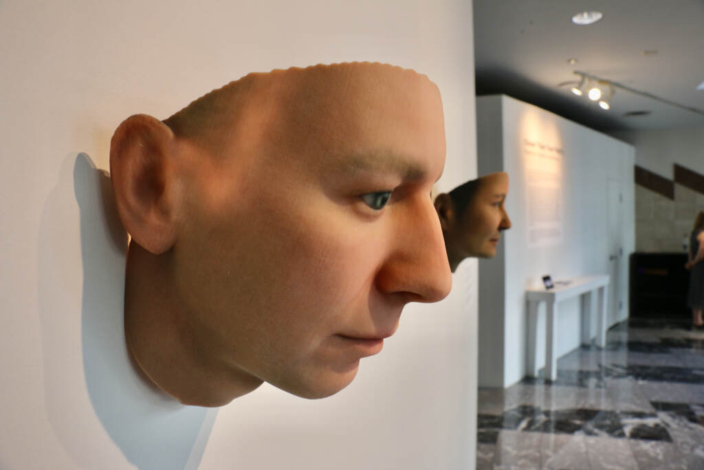 A close-up of a 3D image of a person's face, displayed on a wall.