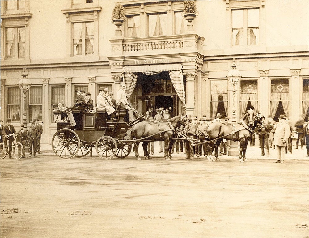 An old sepia-toned photo shows horse-drawn carriages outside of a hotel.