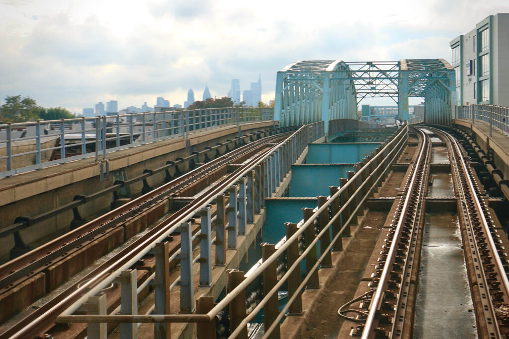 A skyline in the distance, in the foreground are train tracks receding into the distance.